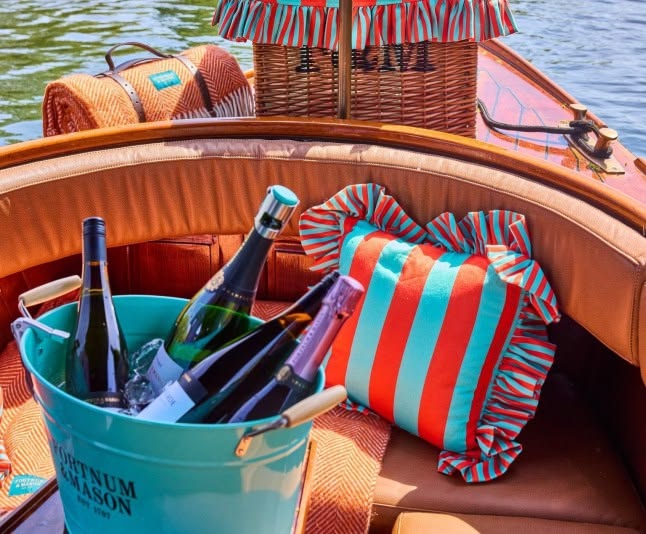 Bottles in blue bucket, striped pillows, and baskets on a boat.