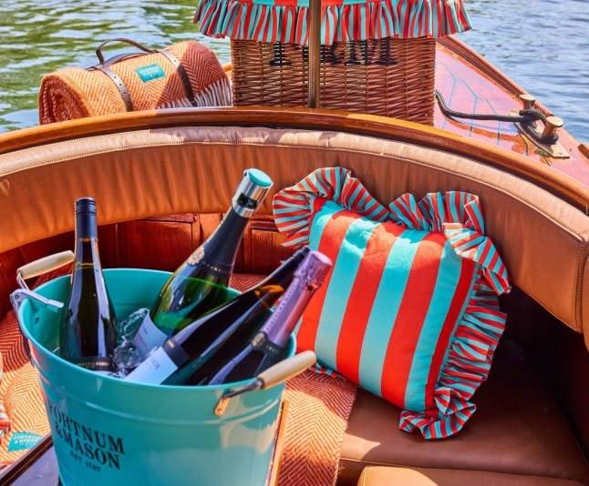Bottles in blue bucket, striped pillows, and baskets on a boat.