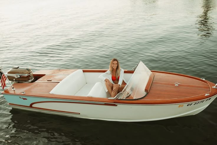 Woman sitting in a small wooden boat on a calm lake.