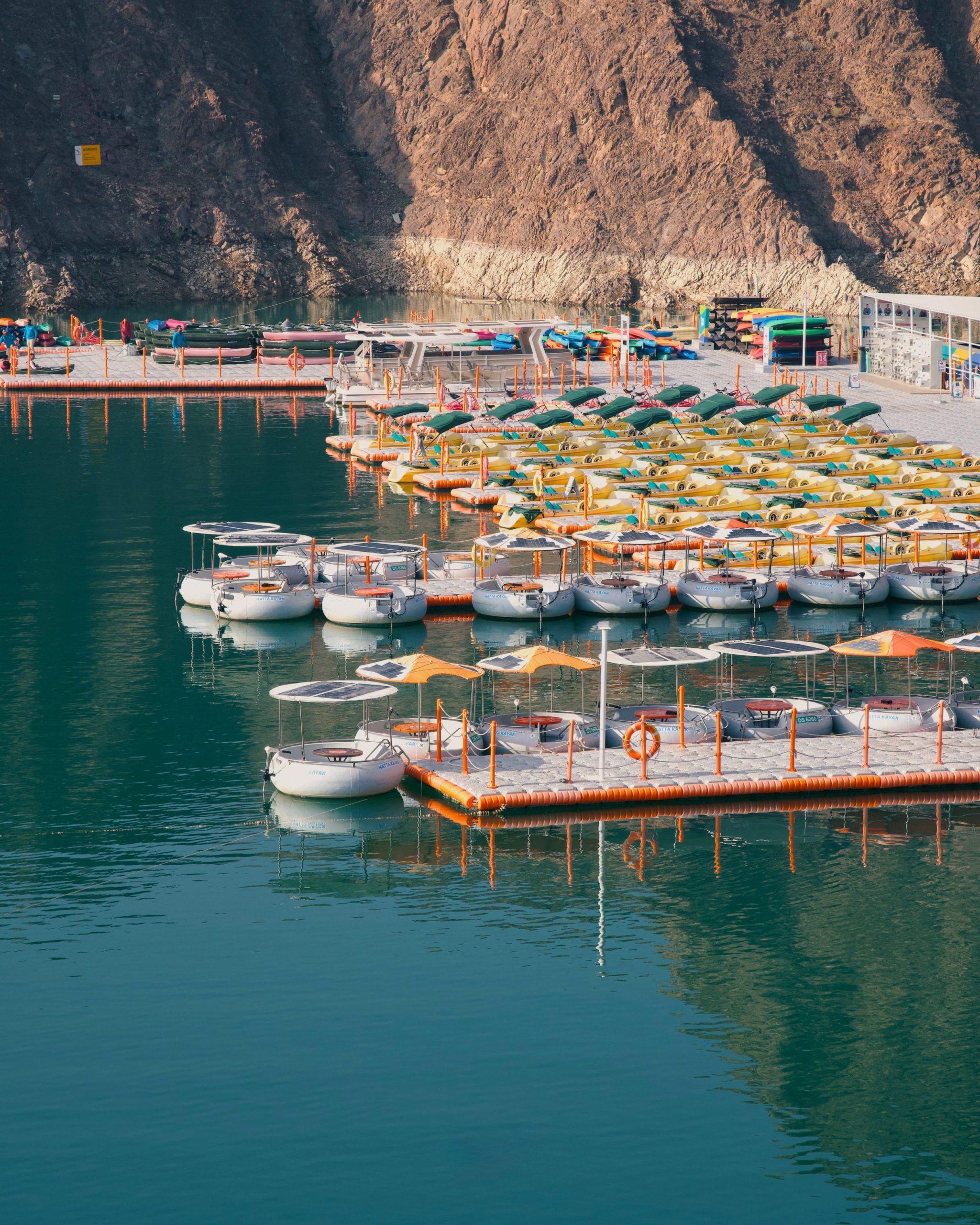 Boats docked at a marina with rocky hills in the background.